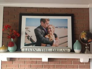 "Livin' the Dream" sign on the mantle piece under wedding day photo of man and woman.