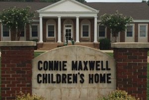 Connie Maxwell Children's Home building with sign out front. Small statue of children playing.