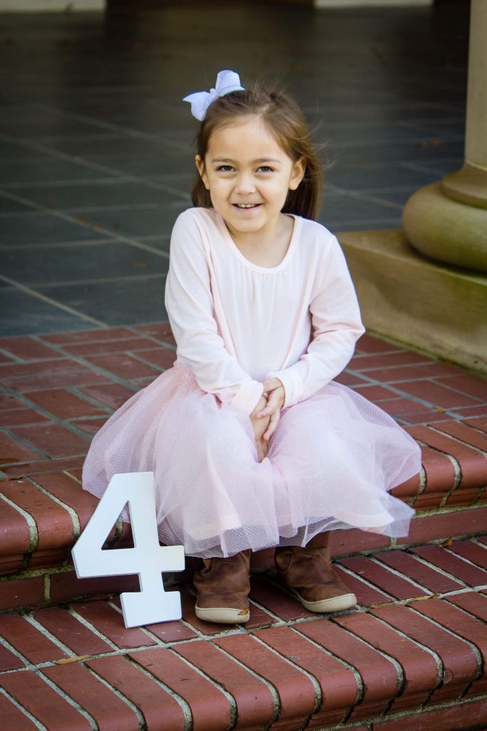 Little girl in pink dress with number 4