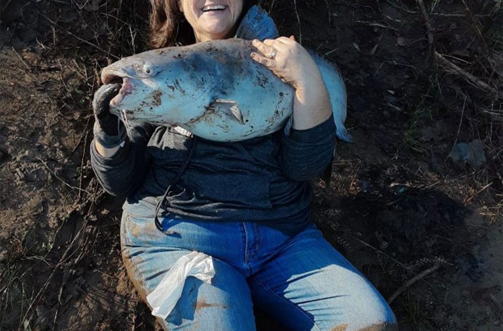 maria covered in mud with a large fish