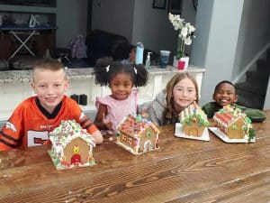 four children building gingerbread houses