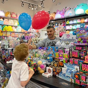 Boy receiving birthday balloons from store manager