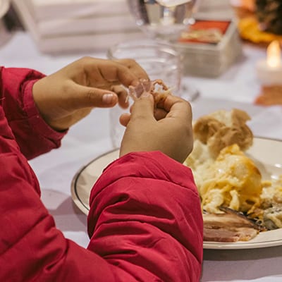 child's hands eating Thanksgiving meal