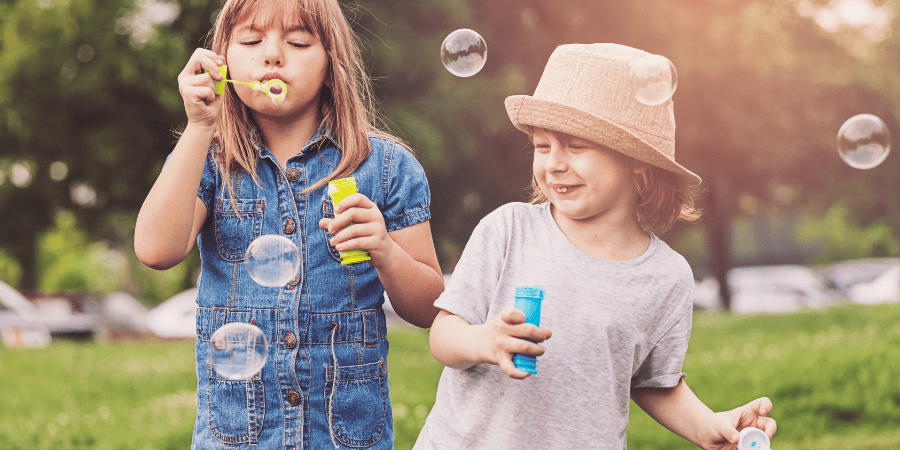 Sisters blowing bubbles in the park