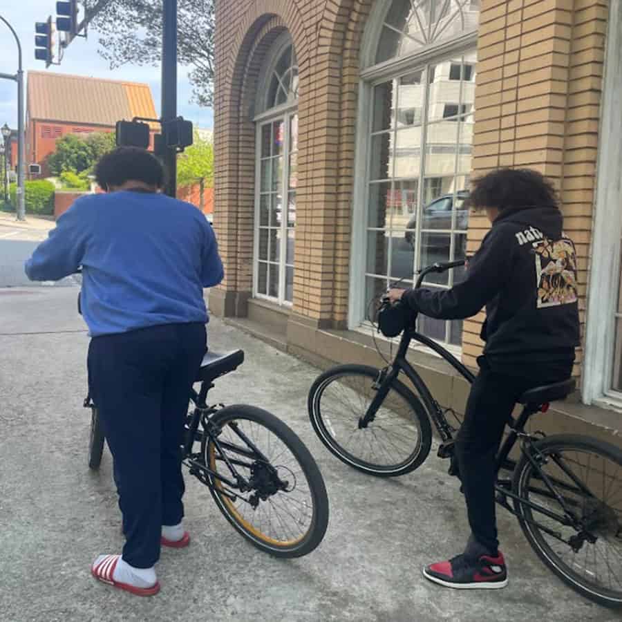 Brothers walking their bikes down a street